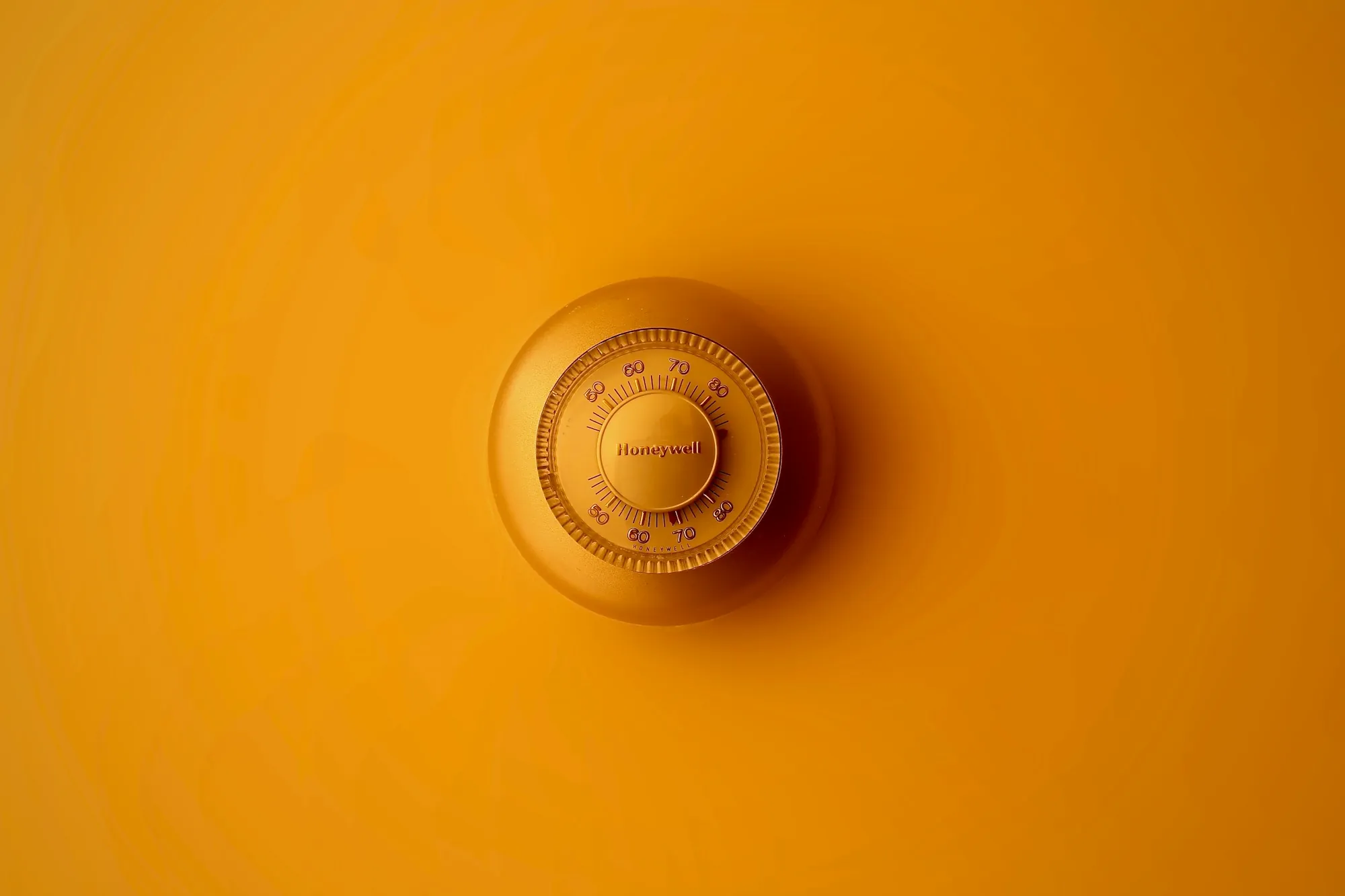 Round dial thermostat on a yellow wall