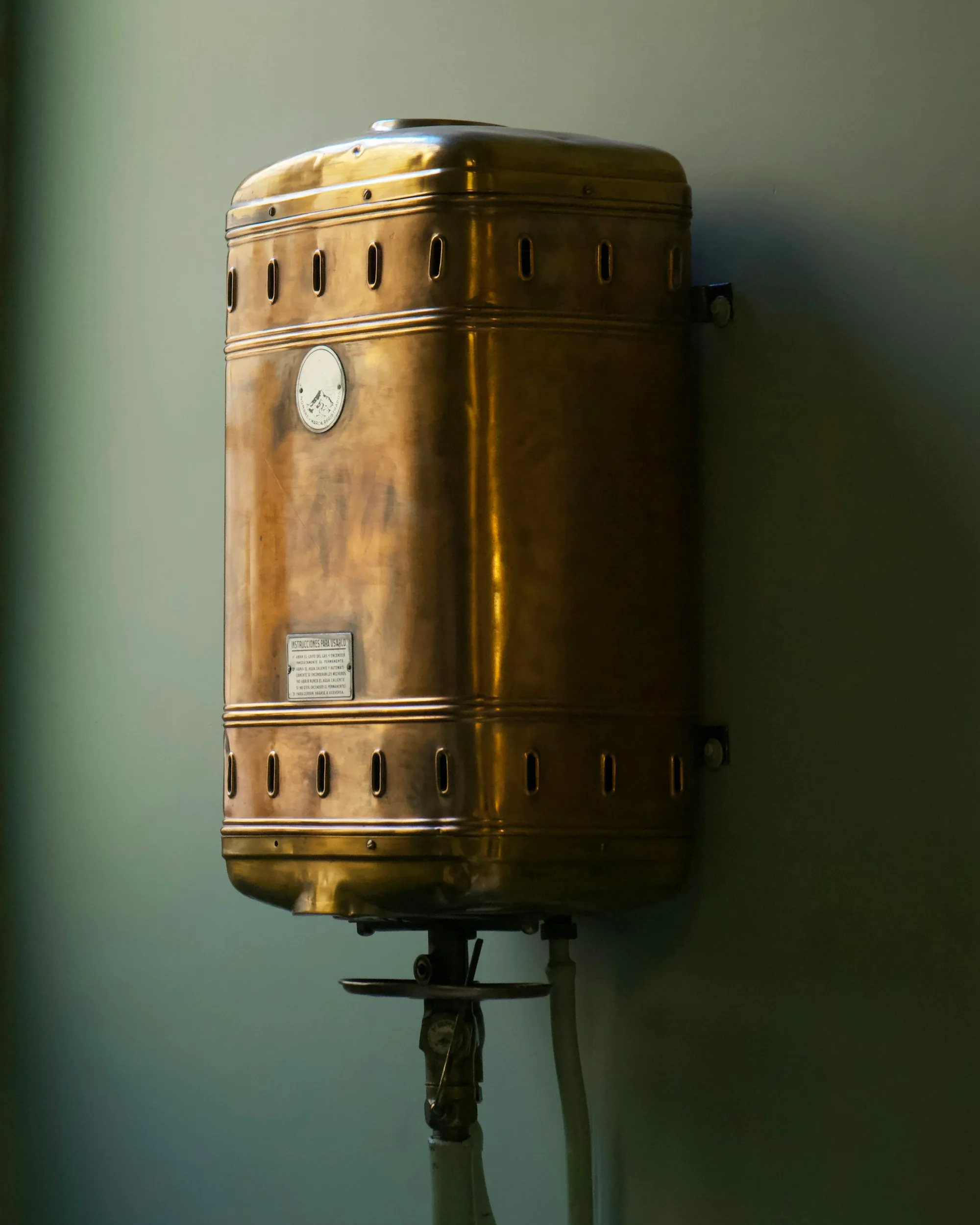 Copper water heater tank mounted on a green wall