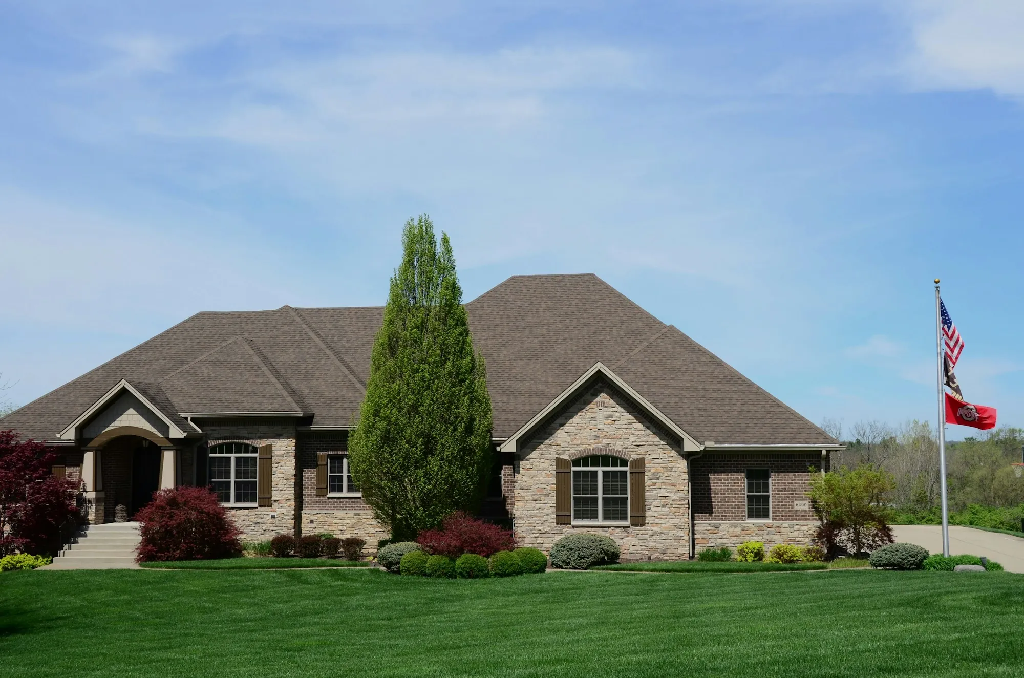 Brick home with an evergreen tree and an American flag